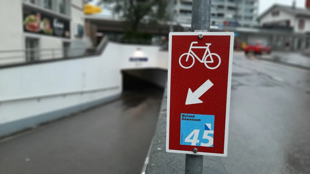 Ein Hinweisschild für Velofahrer vor einer Unterführung. 
